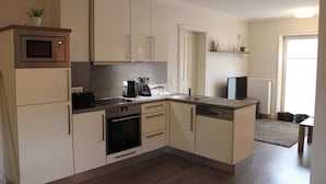 A compact kitchen with a microwave, oven, coffee maker, and dishwasher. - Altstadt Villa Wohnung 3 Memmert (Borkum)