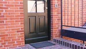 A black door with a window, a metal handrail, and a brick staircase leading up to a door. - Altstadt Villa Wohnung 3 Memmert (Borkum)