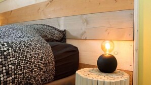 Een bed met beddengoed met een patroon en een ronde, verlichte tafellamp.
