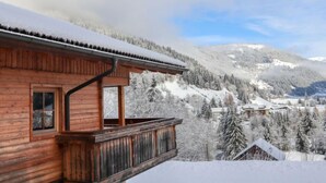 Een houten hut met een balkon met uitzicht op een besneeuwd berglandschap.