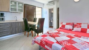 Een compacte slaapkamer met een bed, een eettafel en een kitchenette.