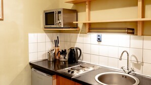 Une cuisine équipée d’un évier en acier inoxydable, d’un four à micro-ondes et de meubles de rangement en bois.
