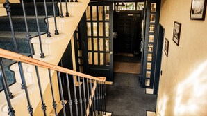 Un escalier avec des rampes noires et des marches de couleur beige, menant à une porte sombre dotée de panneaux de verre.