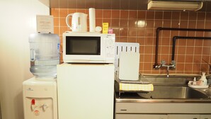 A kitchen with a microwave, water dispenser, and a sink. - Holiday Homes TSUBOYA 4th (Naha)