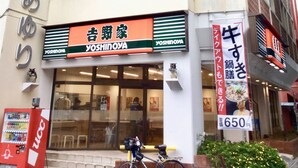 A building with multiple signs, including one for 'Yoshinoya' and another for a restaurant. - Holiday Homes TSUBOYA 4th (Naha)