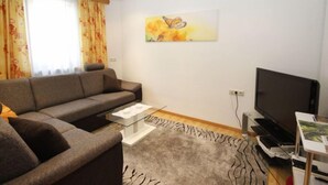 Ein modernes Wohnzimmer mit grauem Sofa, einem Flachbildfernseher, einem Couchtisch und einem Zebra-Teppich.