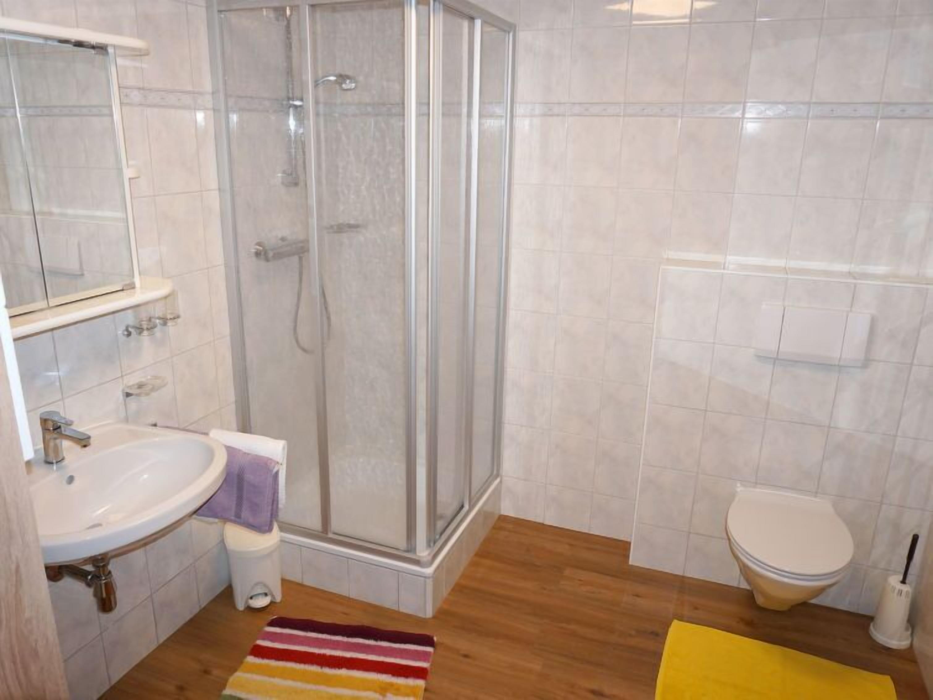 Une salle de bain équipée d’une douche, de toilettes, d’un lavabo et d’un miroir.