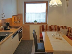A compact kitchen with a dining area, a window with a plant, and a sofa with striped cushions.