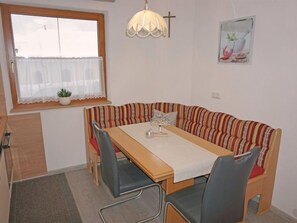 A dining area with a wooden table, striped sofa, and chairs.