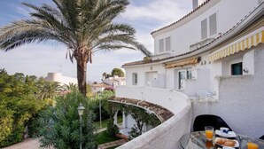 A balcony with a table set for breakfast, surrounded by lush greenery and a palm tree. - Oasis Beach by Interhome (Dénia)