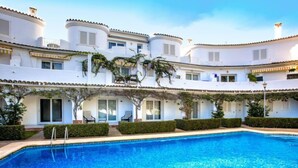 A swimming pool with a clear blue water surface, surrounded by white buildings with balconies and covered outdoor seating areas. - Oasis Beach by Interhome (Dénia)