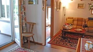 A cozy living room with a sofa, a wooden chair, a coffee table, and a patterned rug. - Tre G OG by Interhome (Solduno)