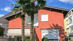 A two-story house with a red facade, white shutters, and a small balcony. - Tre G OG by Interhome (Solduno)