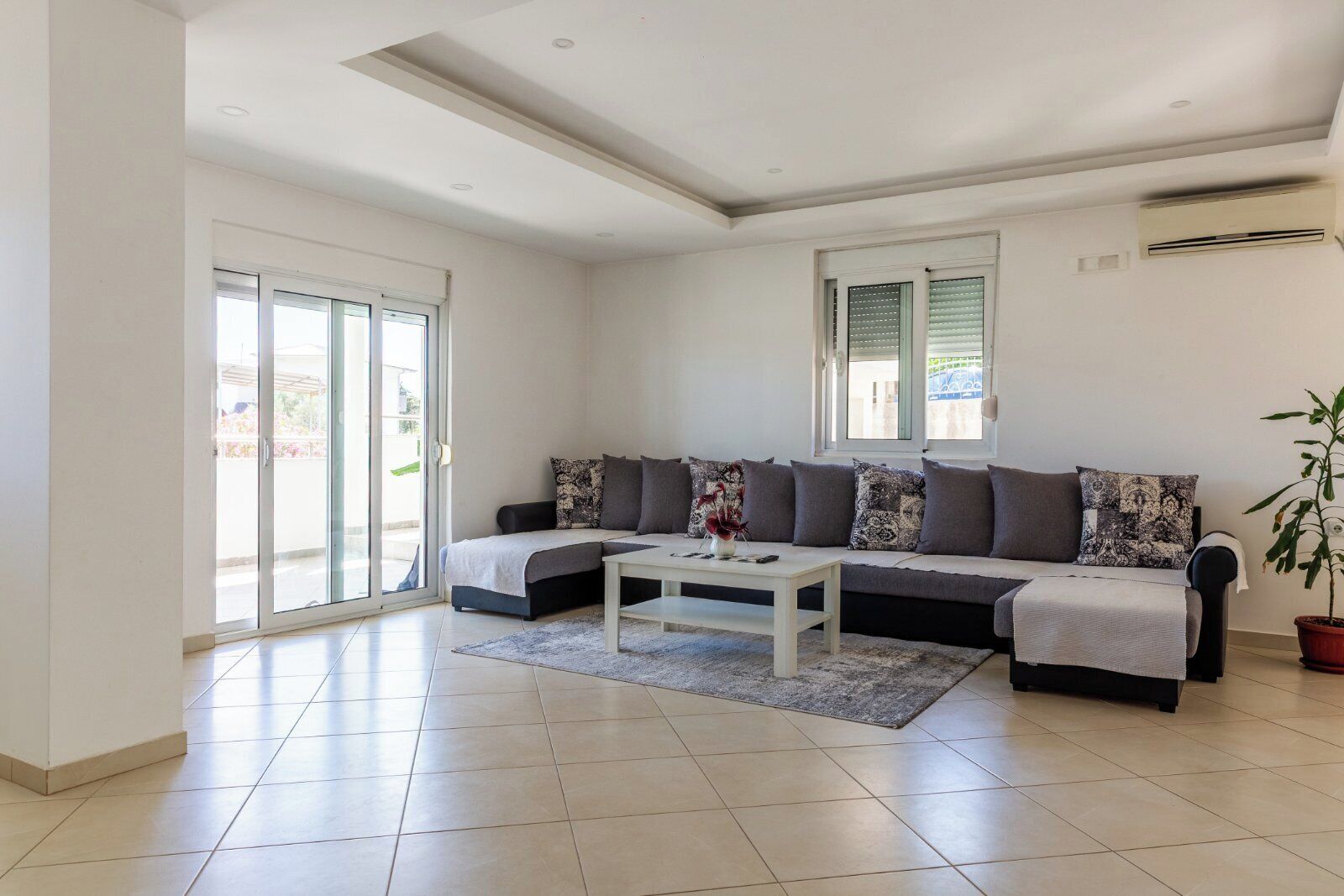 A modern living room with a sectional sofa, a coffee table, and a potted plant.