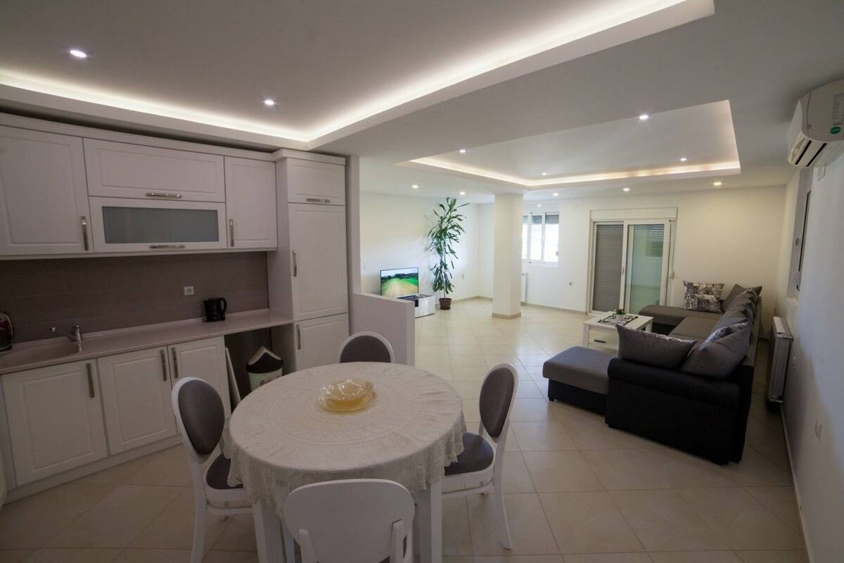 A modern kitchen with white cabinets and a dining area with a round table and chairs.