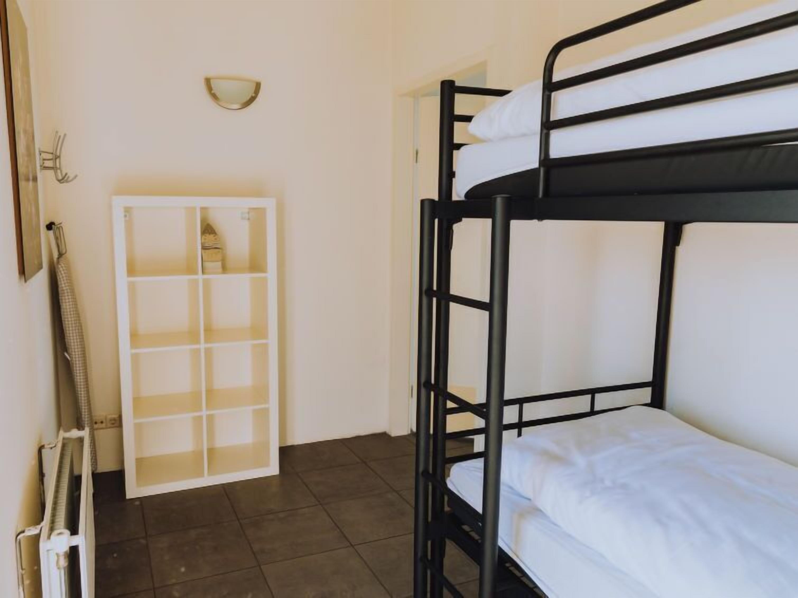 A bunk bed room with a white cabinet and a wall-mounted light fixture.