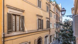 Eine schmale Straße mit Gebäuden, die Rundbogenportale und Fensterläden zeigen.