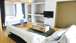 Ein modernes Hotelzimmer mit Bett, Sofa, Fernseher und einem kleinen Tisch.