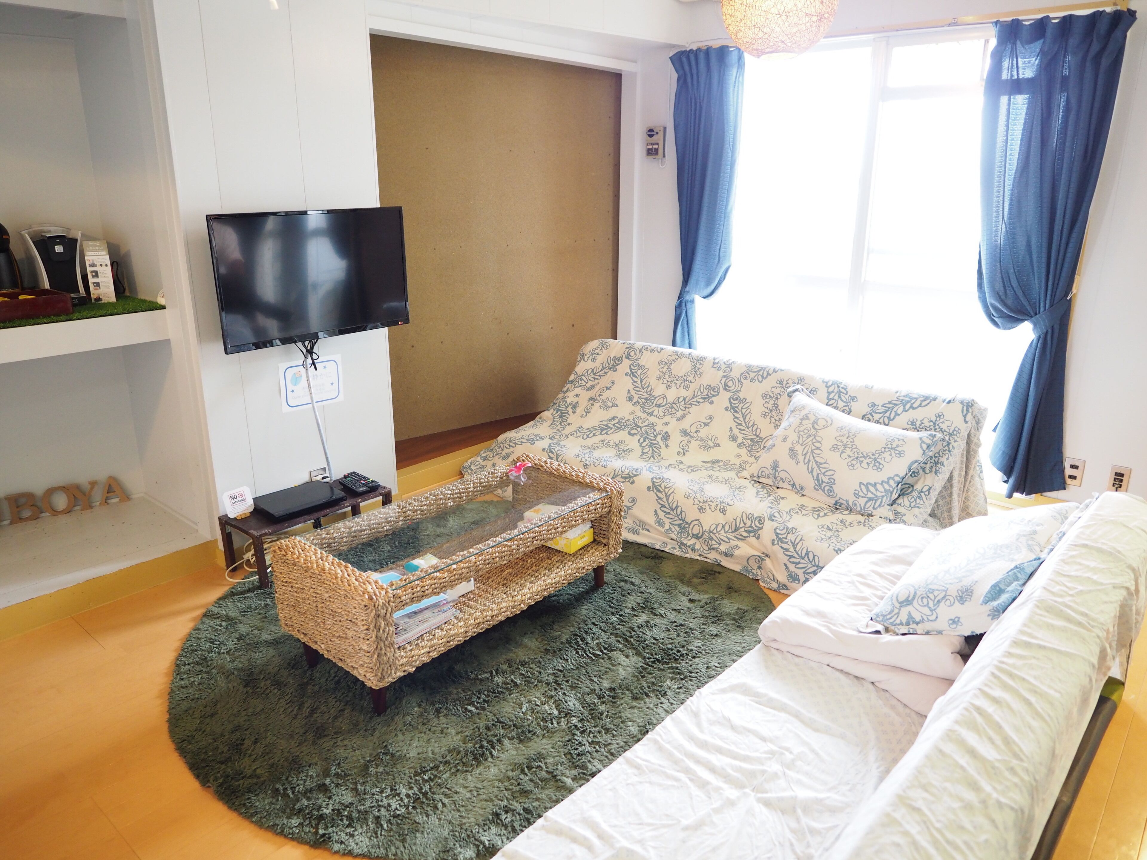 A room with a sofa, a bed, a television, and a small table with a basket.