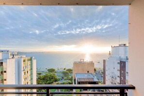 A balcony with a view of a cityscape and a body of water during sunset. - Vista do Mar, Ótimo Local na Beira-mar Norte (Florianópolis)