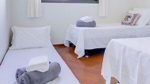 A room with two single beds, a window with blinds, and a curtain. - Vista do Mar, Ótimo Local na Beira-mar Norte (Florianópolis)