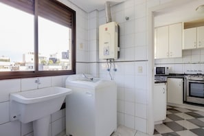 A compact kitchen with a built-in oven, microwave, and a window overlooking the city. - Vista do Mar, Ótimo Local na Beira-mar Norte (Florianópolis)