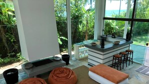 Ein modernes Wohnzimmer mit Essbereich aus Glas, Küchenzeile und Blick ins Freie.
