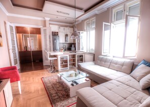 Un salon moderne avec un canapé, une table basse en verre et un tapis rouge.