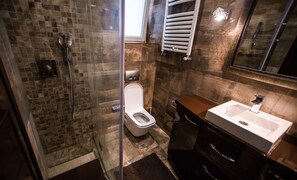 Une salle de bain avec une douche à parois de verre, des toilettes et un lavabo avec un miroir au-dessus.