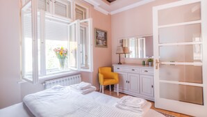 A bedroom with a bed, a chair, a dresser, a mirror, and a window with blinds.