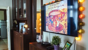 A television displaying a colorful artwork, a remote control, a small potted plant, and a framed picture on a wooden cabinet.