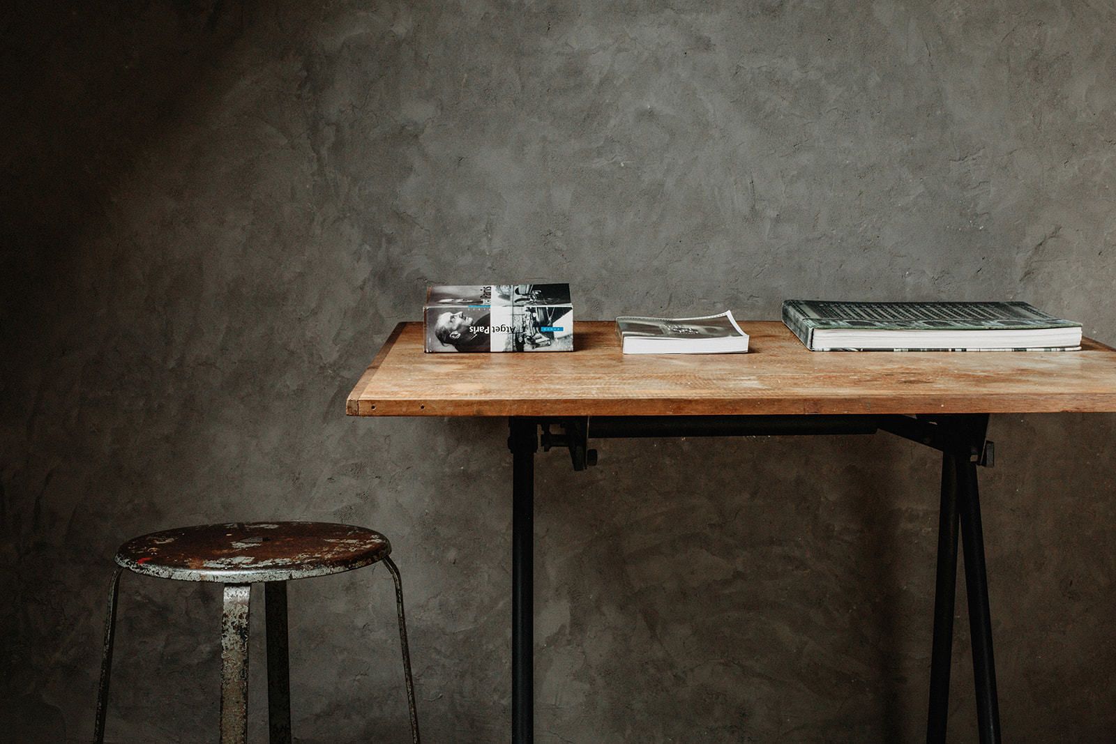 A wooden table with a book, a box, and a notebook.