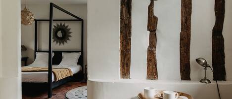 Un dormitorio con una cama con dosel, un espejo redondo y una lámpara colgante.