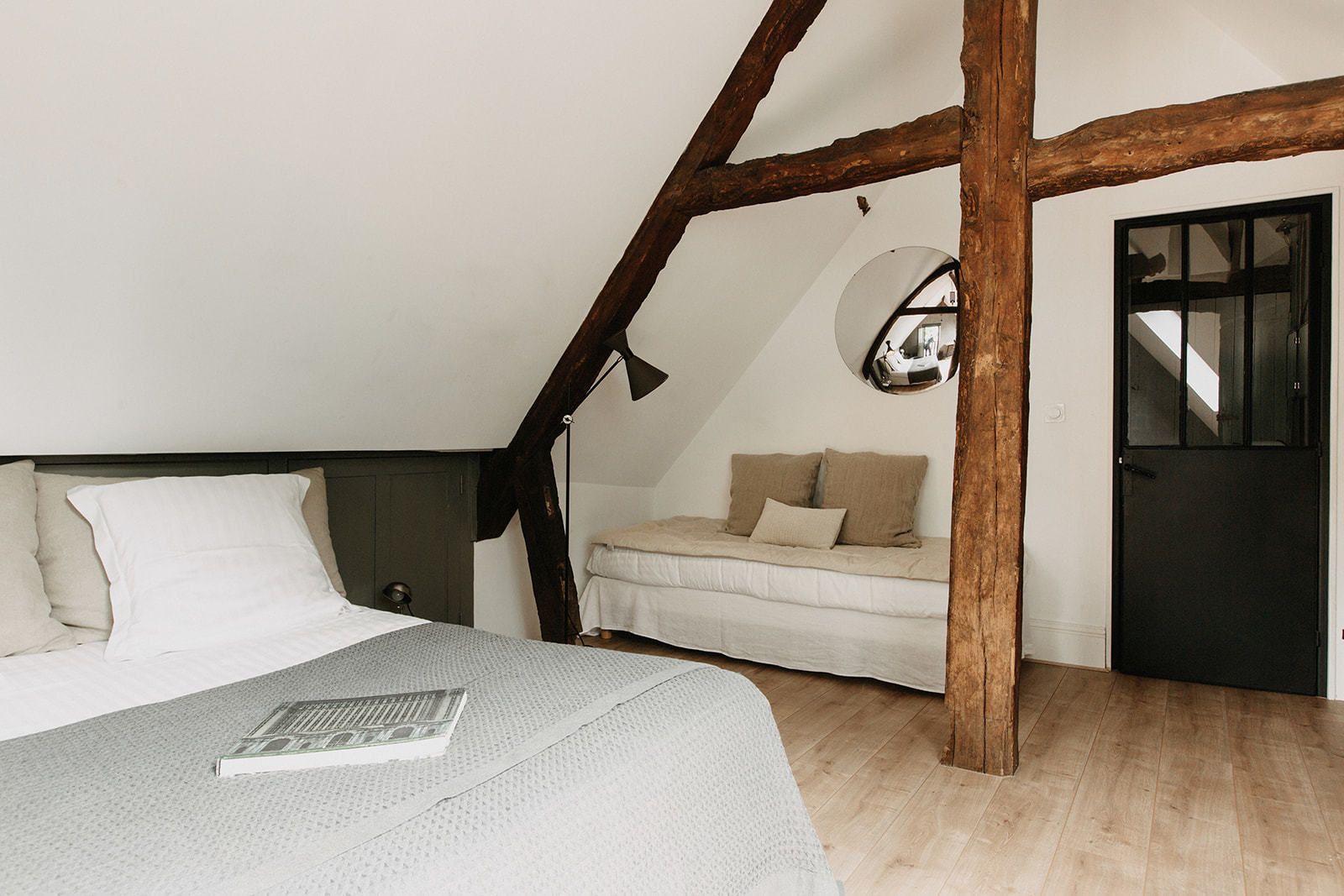 A bedroom with a bed, a sofa, a mirror, and a door.