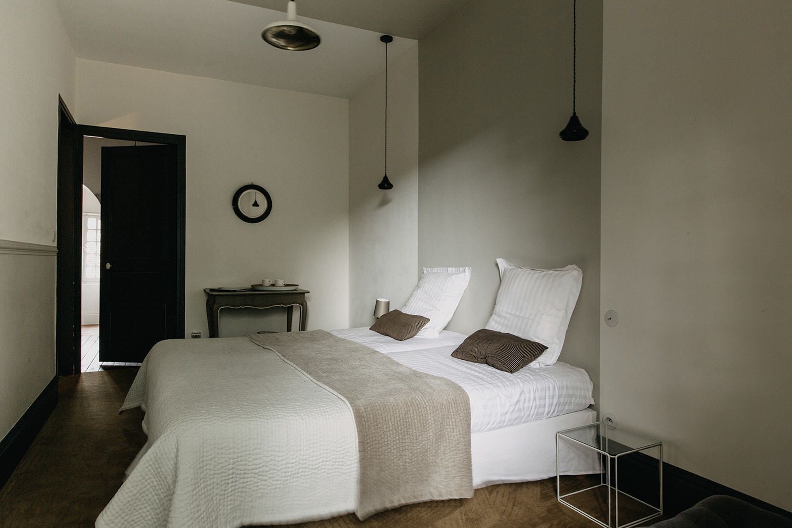 Un dormitorio con cama, mesita de noche, lámpara y un reloj en la pared.