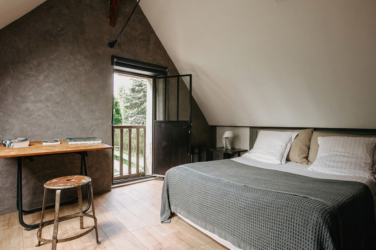 Un dormitorio con una cama, un escritorio y un taburete.