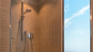 A modern shower with a glass door, a handheld showerhead, and a wall-mounted control.