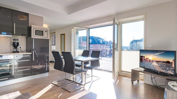 A modern apartment with a kitchen, dining area, and a balcony with a city view.