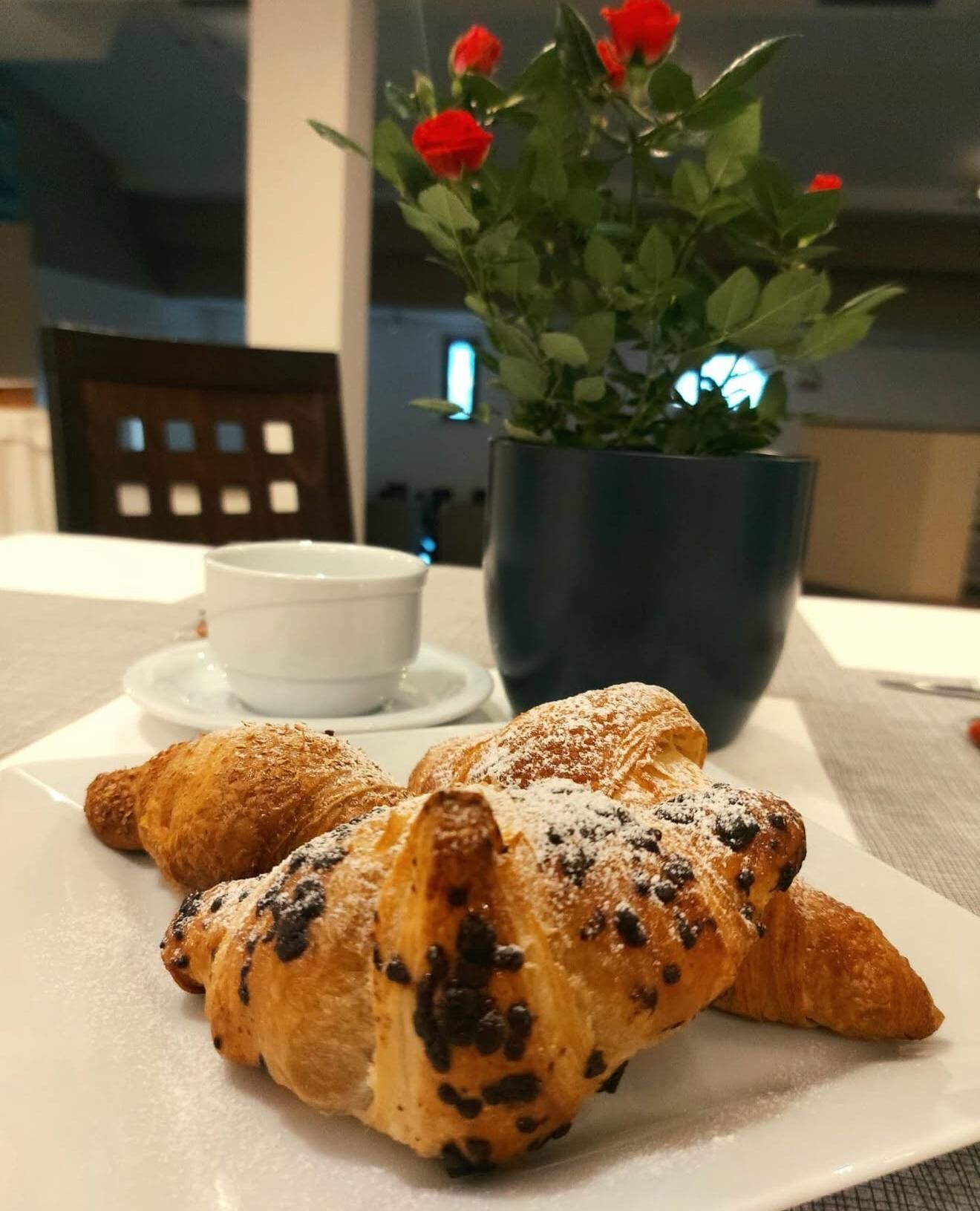 Un plato con cruasanes y una taza de café sobre una mesa.
