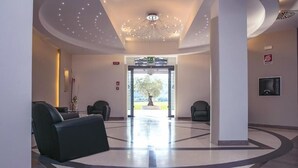 A modern lobby with a central seating area, a decorative ceiling light, and a view of the outdoors through a glass door. - Hotel PentHouse (Perugia)