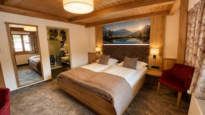 Un dormitorio con una cama grande, techo de madera y un cuadro de un paisaje montañoso.