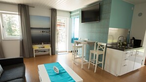 A compact living space with a kitchenette, a dining area, and a seating area. - Seeland Lodge (Hilpoltstein)