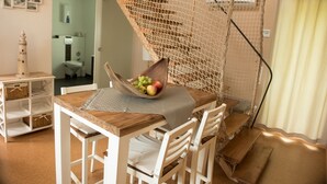 A dining area with a wooden table, white chairs, and a woven basket containing fruits. - Seeland Lodge (Hilpoltstein)