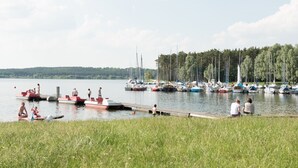 A lakeside marina with boats docked and people engaging in water activities. - Seeland Lodge (Hilpoltstein)