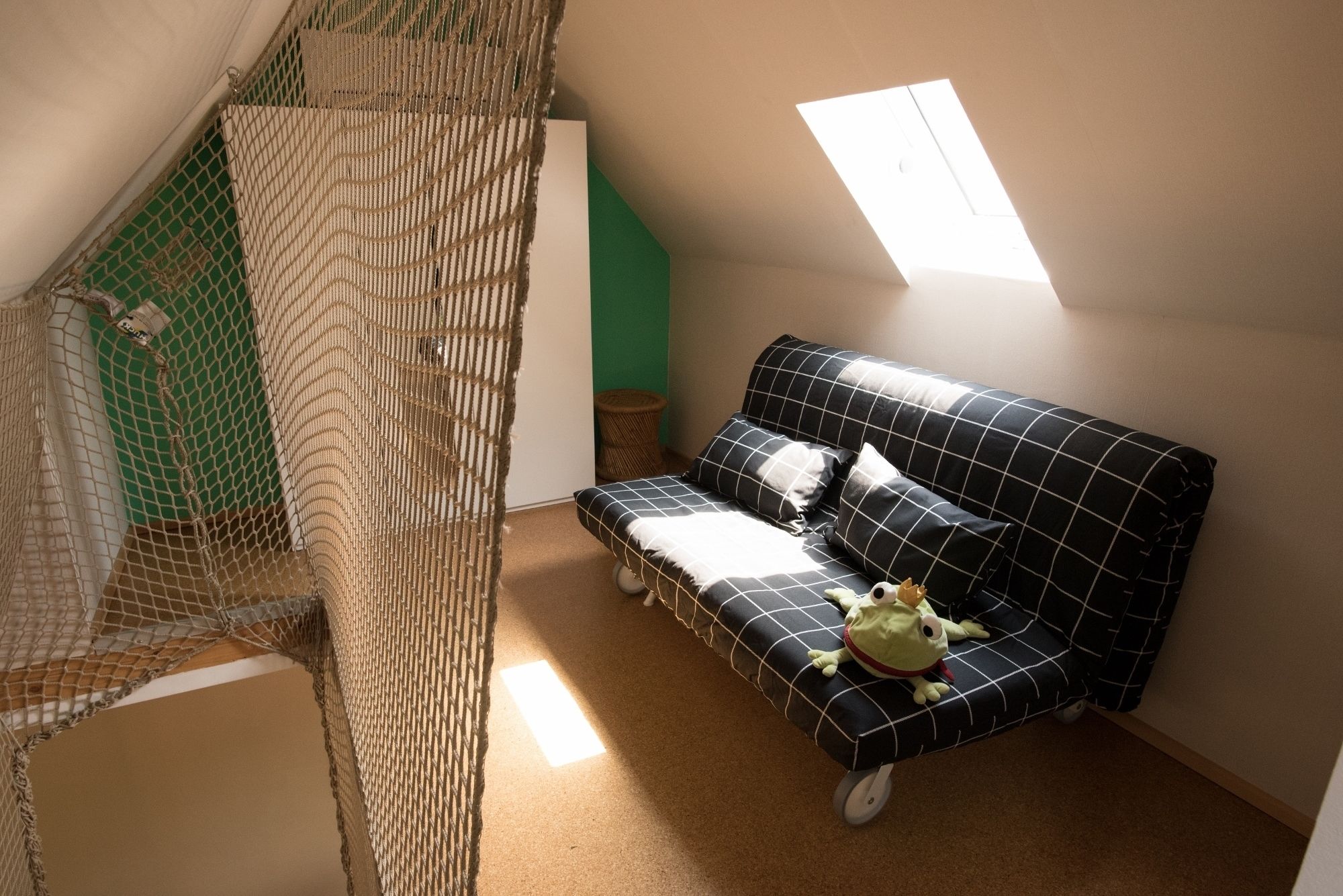 A cozy room with a sofa, a netted play area, and a skylight.