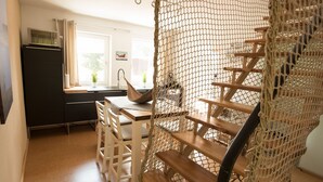 A staircase with a netted railing, wooden steps, and a kitchen area with a microwave, sink, and potted plants. - Seeland Lodge (Hilpoltstein)