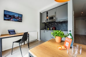 A modern kitchen with grey cabinets, a microwave, and a potted basil plant on the counter. - Brera Serviced Apartments Leipzig (Leipzig)