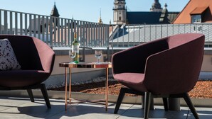 A terrace with two modern chairs and a small table, featuring a bottle of wine and glasses. - Brera Serviced Apartments Leipzig (Leipzig)