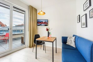 Una sala de estar moderna con un sofá azul, una mesa de madera y un televisor montado en la pared.