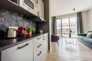 A modern kitchen with a black countertop, stainless steel appliances, and a potted plant. - Brera Serviced Apartments Leipzig (Leipzig)
